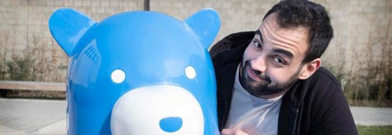 Miś na ławce 3 Mężczyzna obok niebieskiego posągu misia.