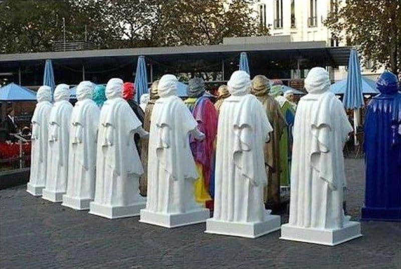 Replika pomnika Beethoven 4 Ludzie przebrani za posągi w białych i niebieskich szatach w parku miejskim.