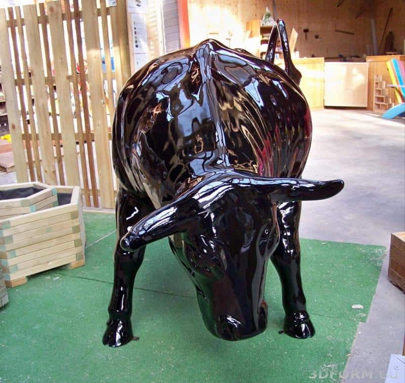 Duża eventowa figura byka 5 Czarna, błyszcząca rzeźba byka w pozycji pochylonej do przodu, umieszczona na zielonej sztucznej trawie w pomieszczeniu.