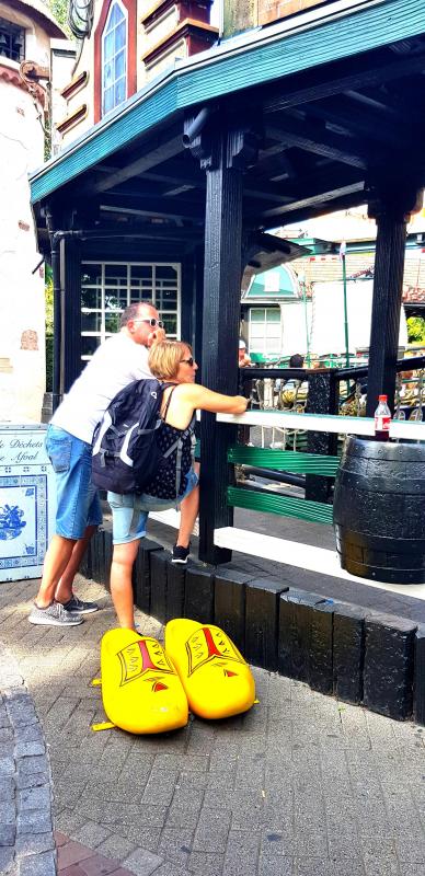 Wielkie chodaki 3 Para osób w żółtych, dużych drewnianych butach pozuje do zdjęcia przed budynkiem w stylu holenderskim.