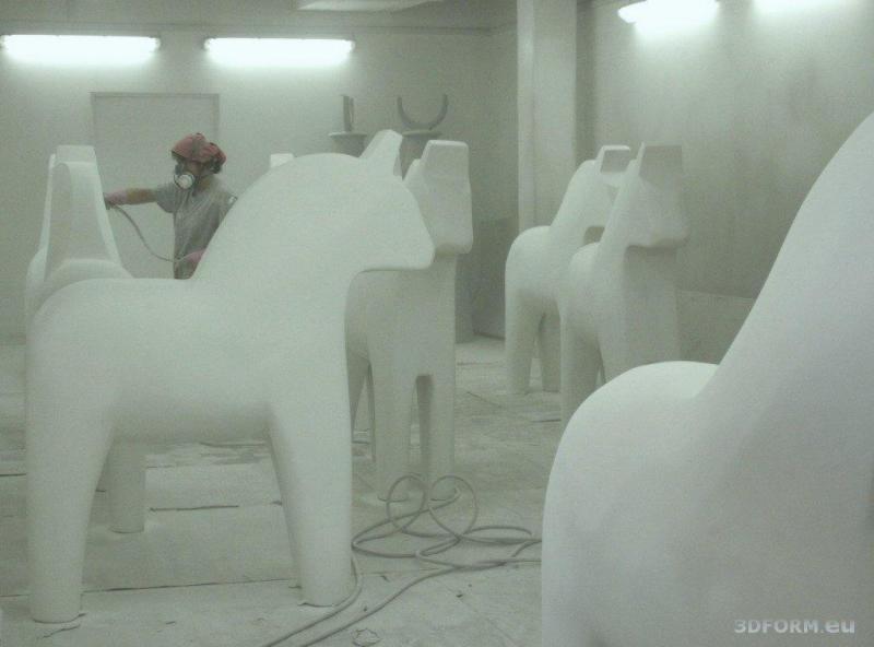 Artystycznie malowane konie z Dalarna 3 Osoba malująca duże figury koni w warsztacie.