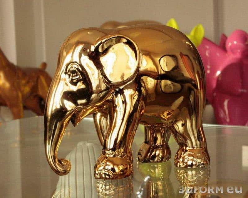 Figurka złotego słonia na szklanym stole.