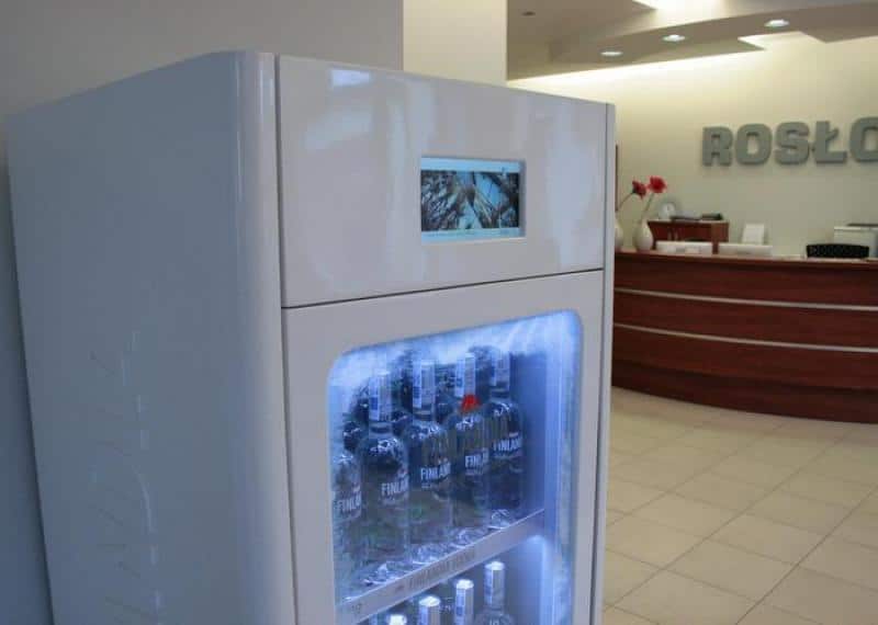 Witryna chłodnicza FINLANDIA 2 Lodówka z napojami w recepcji firmy. W tle biurko recepcyjne i neonowy napis na ścianie.