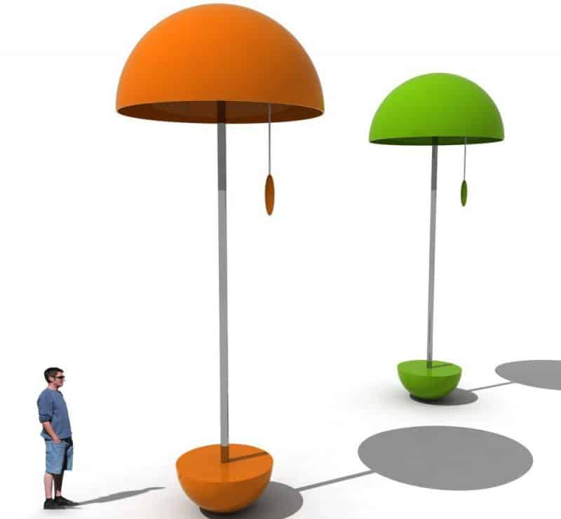 Lampy festiwalowe 3 Dwie duże, nowoczesne lampy z pomarańczowym i zielonym abażurem, obok nich stoi człowiek.