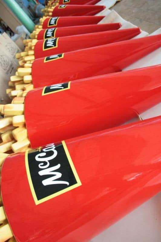 Reklamowe frytki McCain 1 Czerwone pudełka na frytki z logo McCain ustawione w rzędzie na stole.