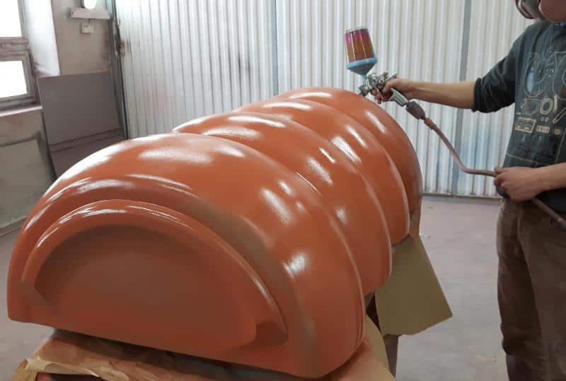 Mentos reklama 3D billboard 3 Osoba malująca pistoletem natryskowym duży, pomarańczowy element.