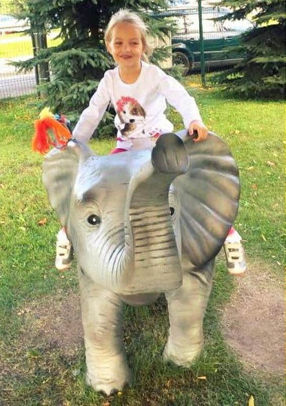 Figury w parku tematycznym 5 Dziewczynka siedząca na figurce słonia na placu zabaw.