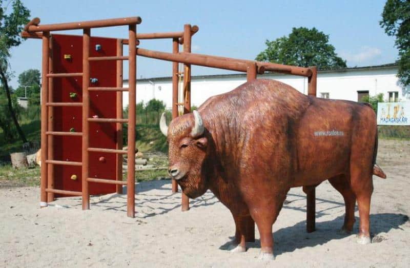 Figury w parku tematycznym 6 Plac zabaw z dużą drewnianą konstrukcją i figurą żubra.