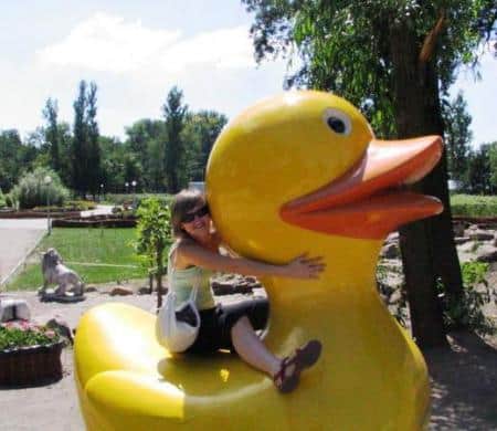 Figury w parku tematycznym 3 Osoba obejmująca dużą plastikową żółtą kaczkę w parku.