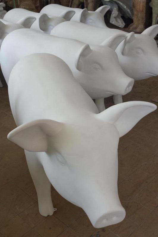 Artystycznie malowane figury zwierząt 3 Białe figury świń ustawione jedna za drugą na drewnianej podłodze.