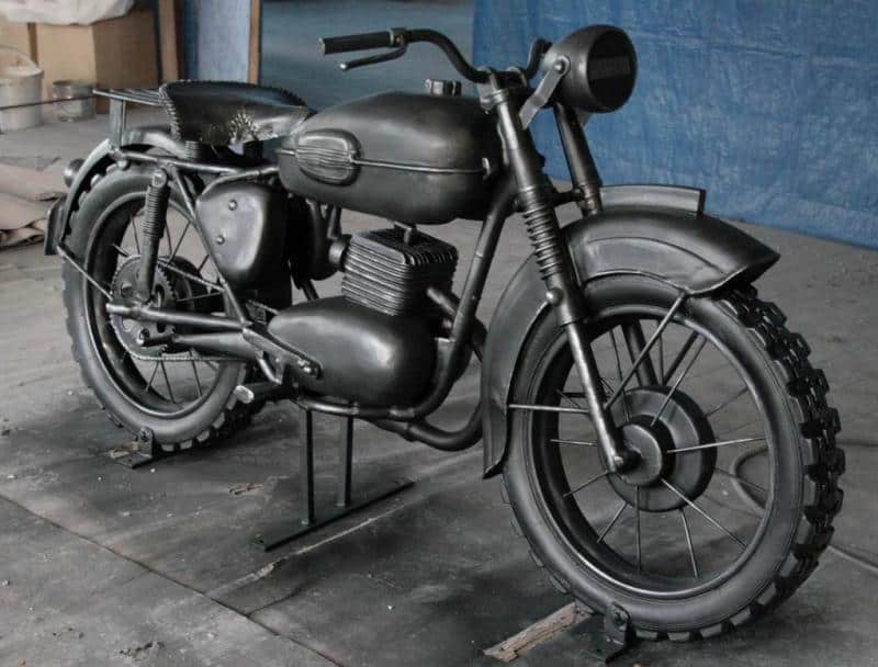 Kultowy Motocykl - Pomnik w Żaganiu 1 Czarny, zabytkowy motocykl na tle niebieskiej ściany.