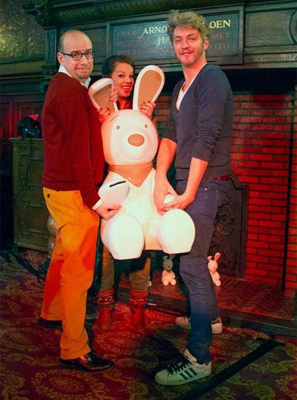 oryg_064490685_1129949550544944_1465385417682452480_o Trzy osoby trzymające dużą figurkę królika w jasnym wnętrzu.