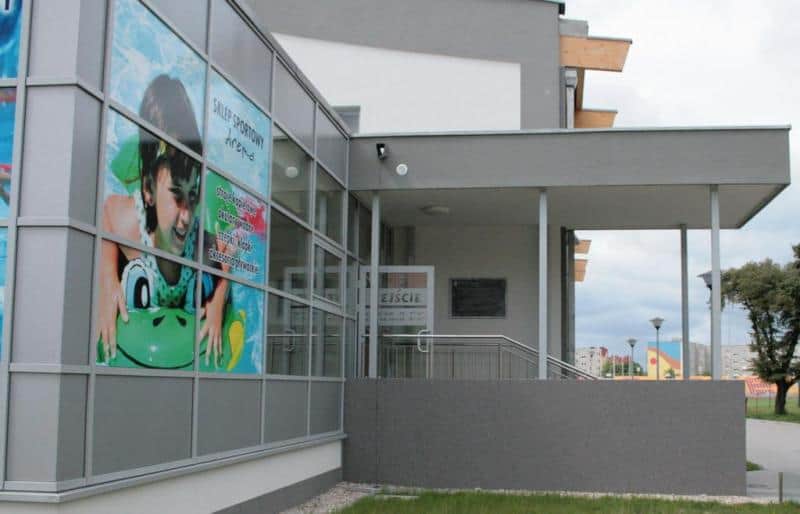 Dekoracyjna tablica informacyjna 3 Budynek z dużym plakatem przedstawiającym dziecko na dmuchanym materacu oraz wejściem z napisem