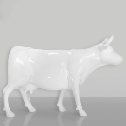 błyszcząca biała ceramiczna figurka krowy na jasnoszarym tle