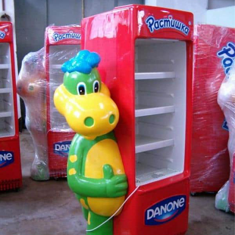 Czerwono-zielona lodówka Danone z maskotką dinozaura.