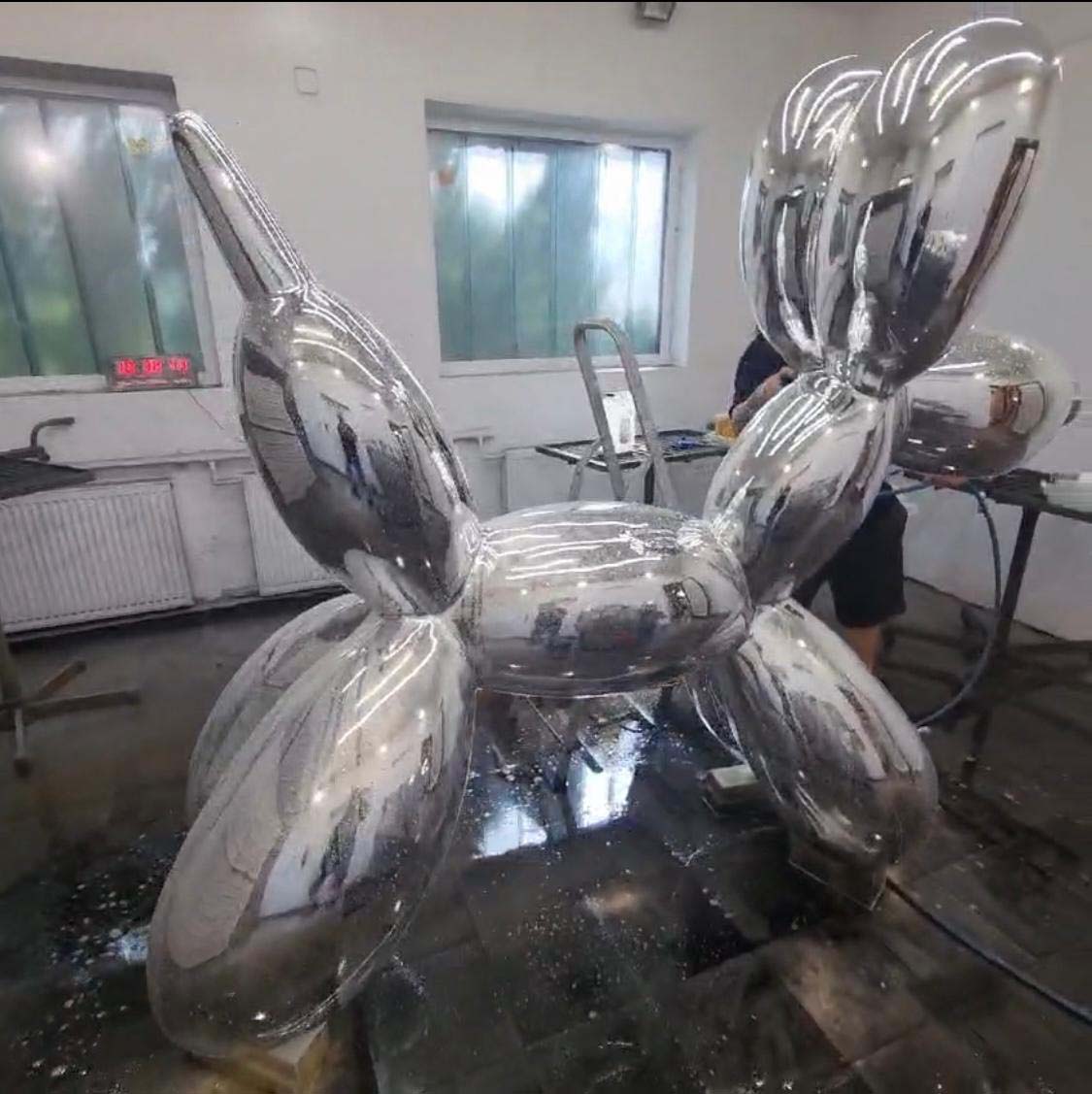 Metaliczna rzeźba psa balonowego w pracowni artystycznej.