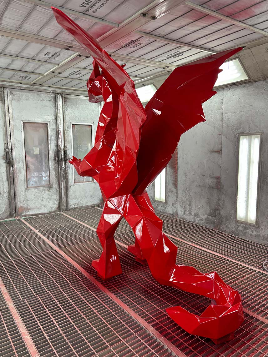 Czerwona, geometryczna rzeźba smoka w warsztacie.