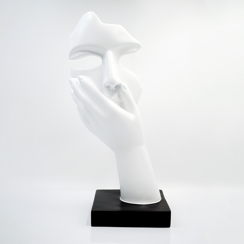 Mała Maska Na Podstawie - Motyw III 5 Biała rzeźba przedstawiająca fragment twarzy zasłonięty dłonią na czarnej podstawie na jasnym tle.