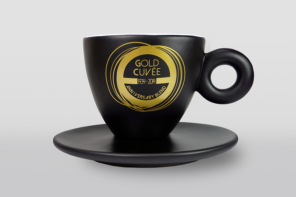 Czarna filiżanka z podstawką, ozdobiona złotym napisem 