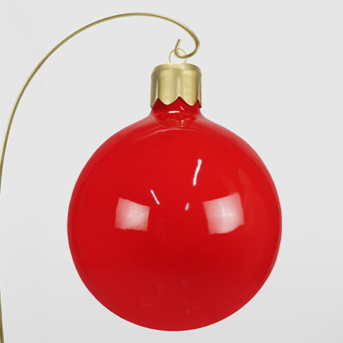 Czerwona błyszcząca bombka choinkowa z złotym uchwytem na białym tle.