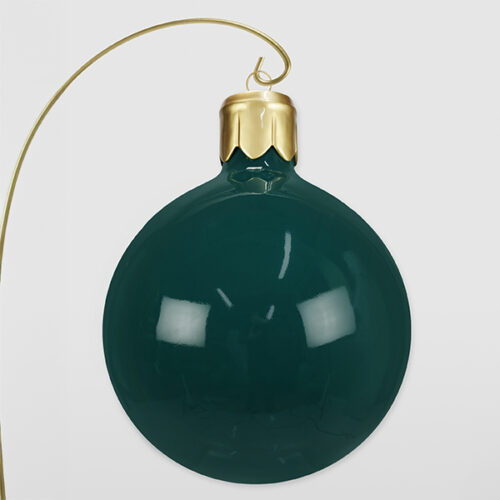 Zielona szklana bombka choinkowa z złotą zawieszką na białym tle