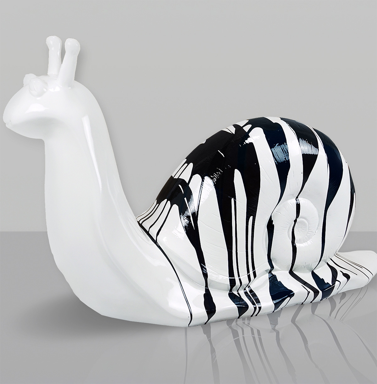 Figura Dekoracyjna Duży Ślimak - Trash 3 Biały model ślimaka z czarno-białą, zdobioną muszlą na szarym tle i odbiciem na błyszczącej powierzchni